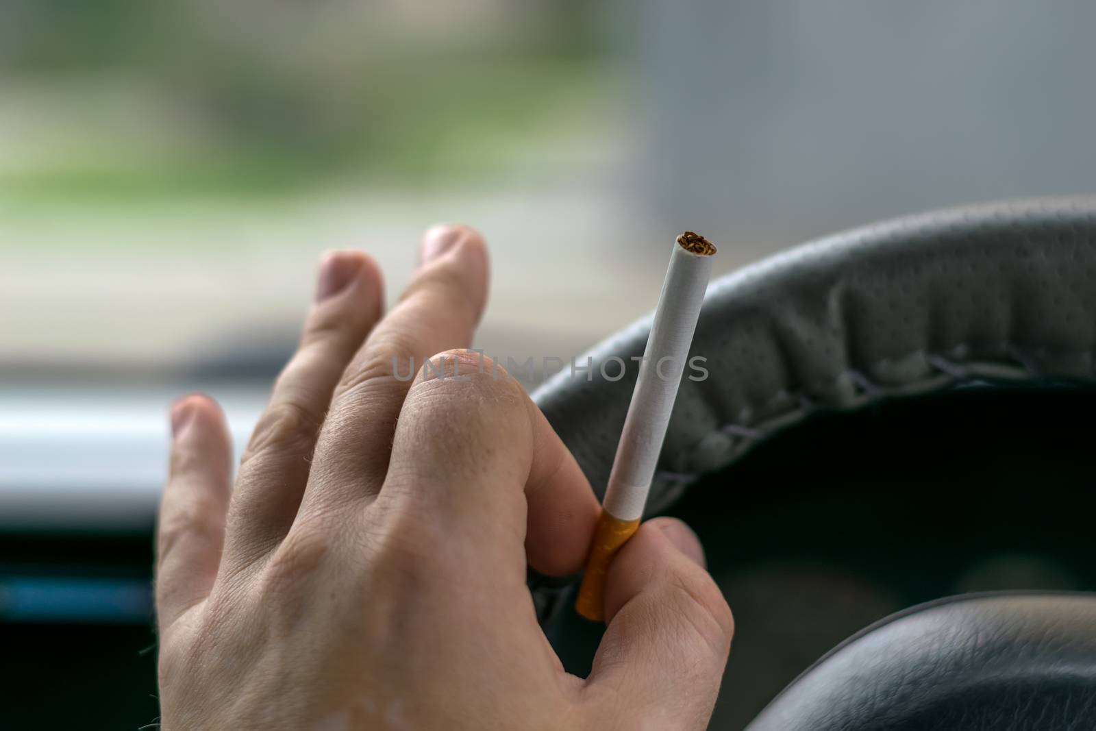 close-up, the hand of the driver of the car holds a cigarette