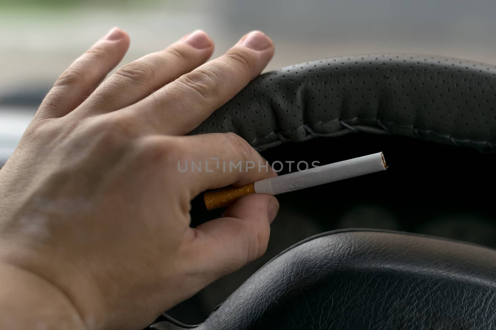 the hand of the driver of the car with skin disease "vitiligo" holds a cigarette by jk3030