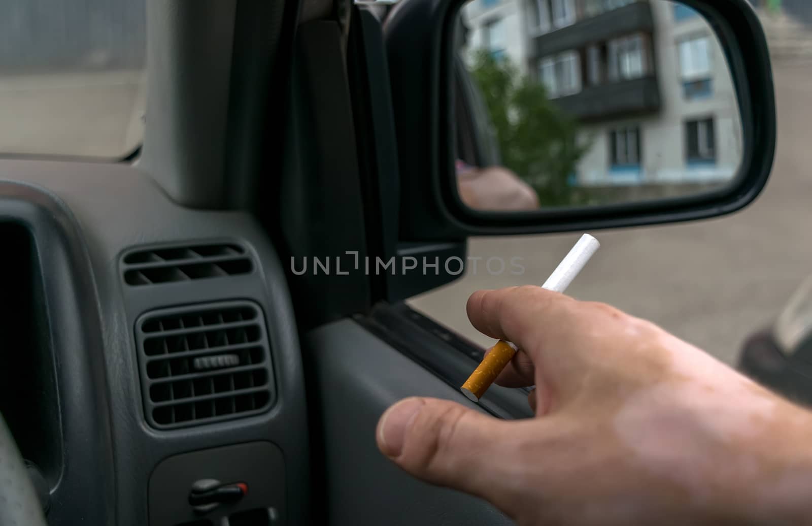 close-up of a cigarette in the hand of a man in the car by jk3030