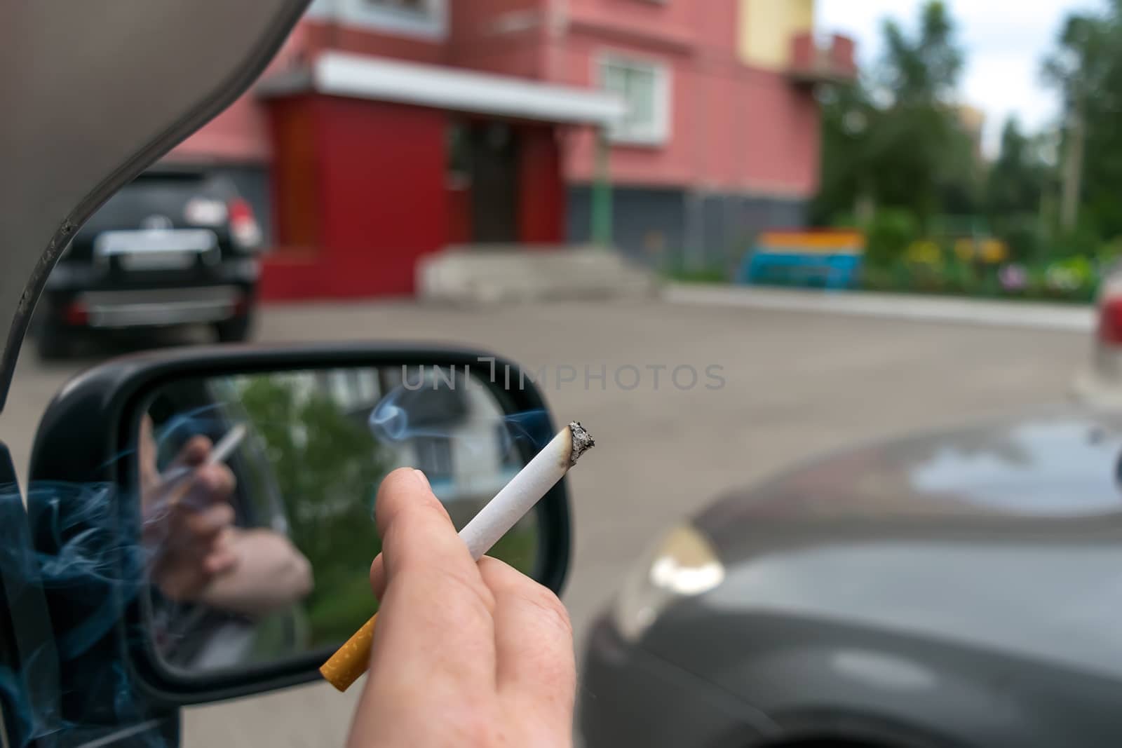 close-up of a cigarette in the hand of a man in the car by jk3030