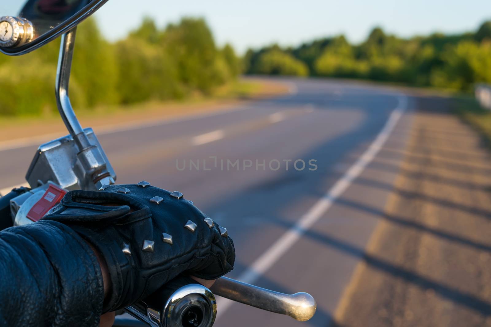 closeup of the hand of the biker on the control handle of the motorcycle and the view of the road