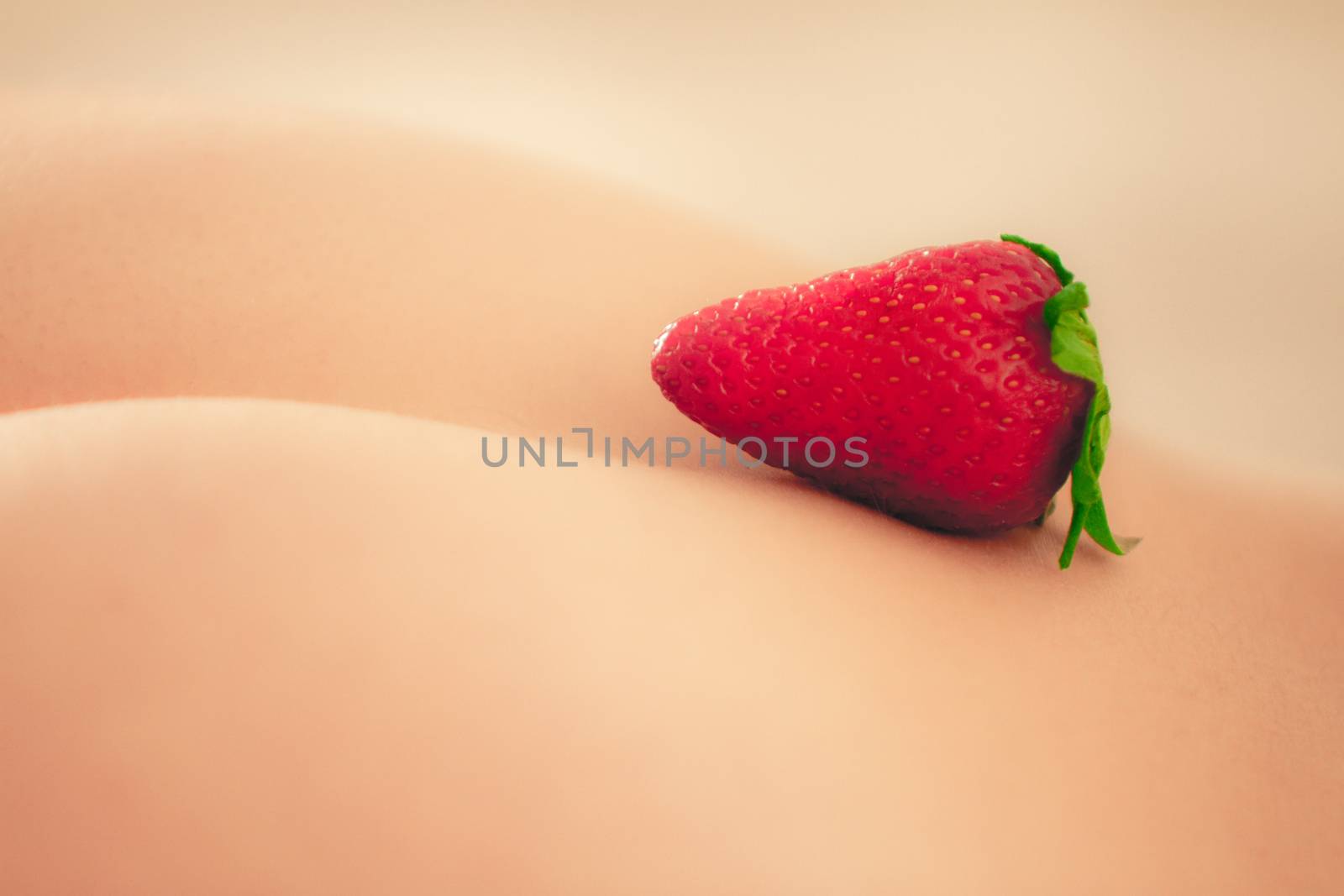Inviting sexy back of a girl with a resting strawberry indicating the attachment of pinkish buttocks