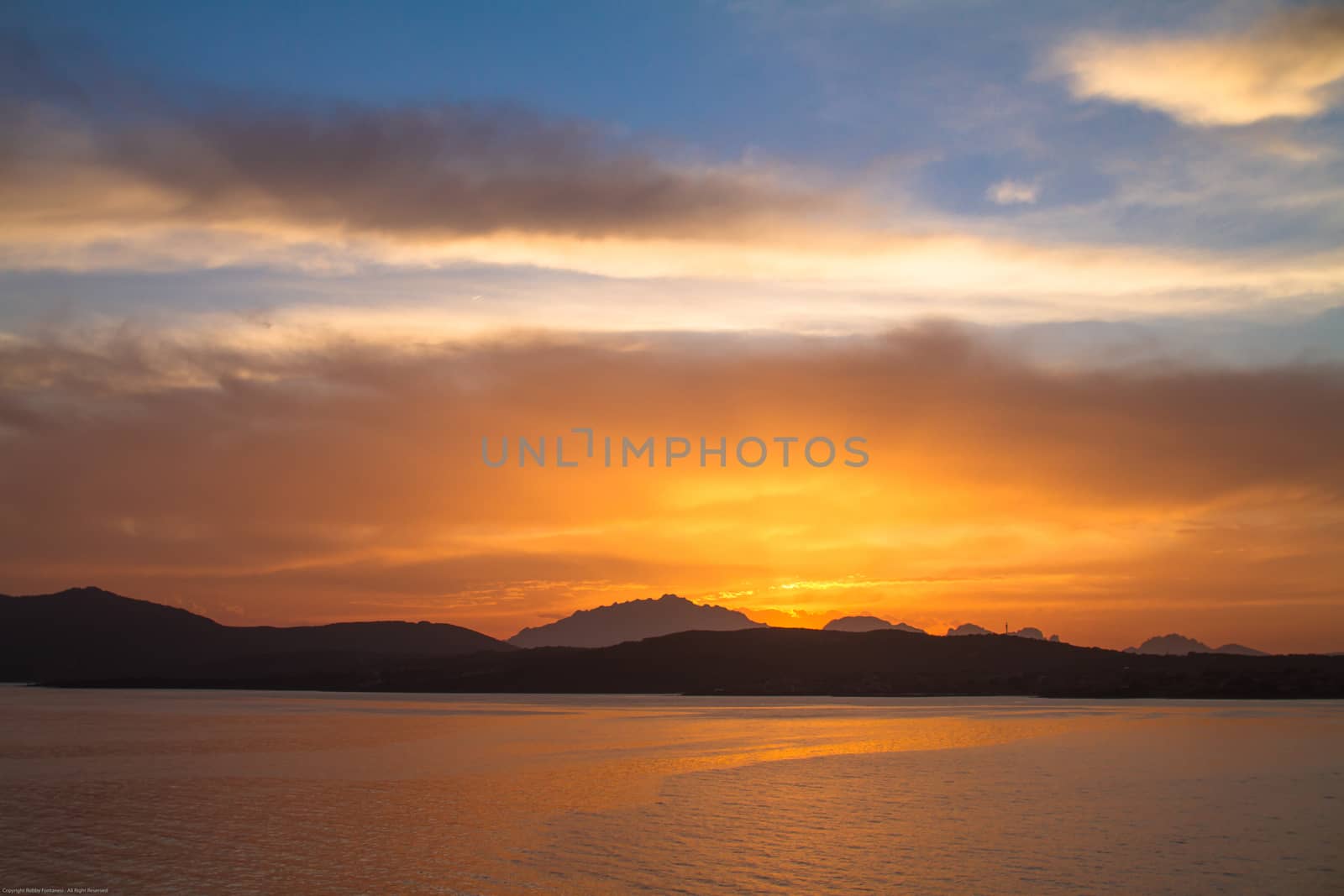 Sunrise on the Sardinian sea coast with intense orange color seen from the sea