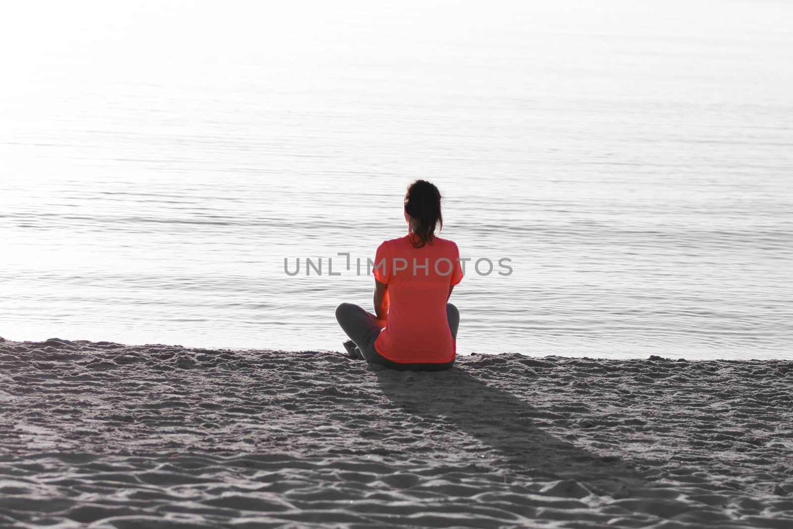 Young woman sitting on the shoreline of the sea at dawn in athle by robbyfontanesi
