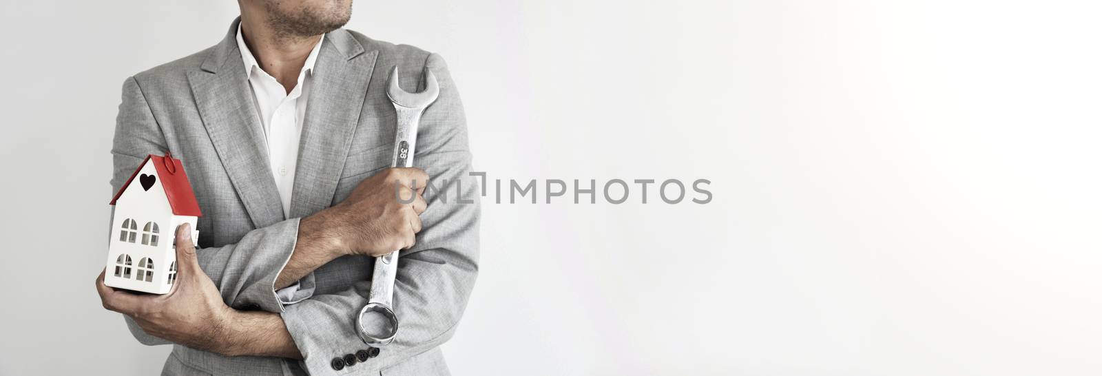 Home Builder. Engineering and Architect. Man on grey suit. Man holding wrench on grey background with copy space. Strong, Professional man, Civil construction worker, Designer.
