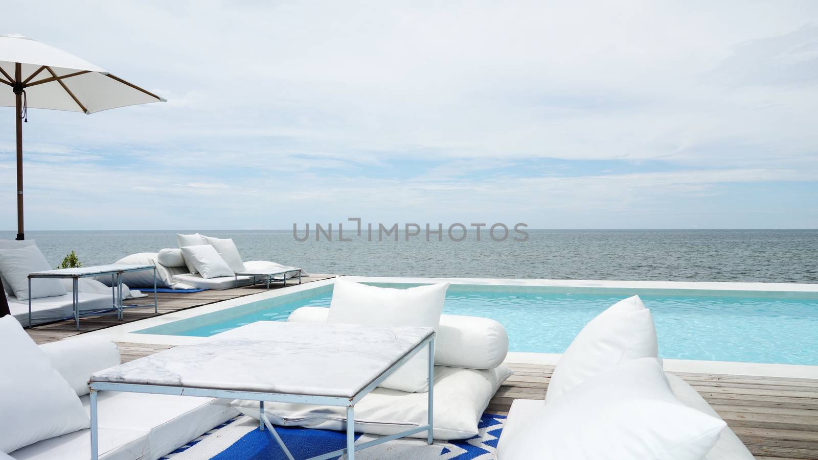 Swimming pool looking at blue sea view and blue sky background. Relax vacation time with nice place at sea beach 