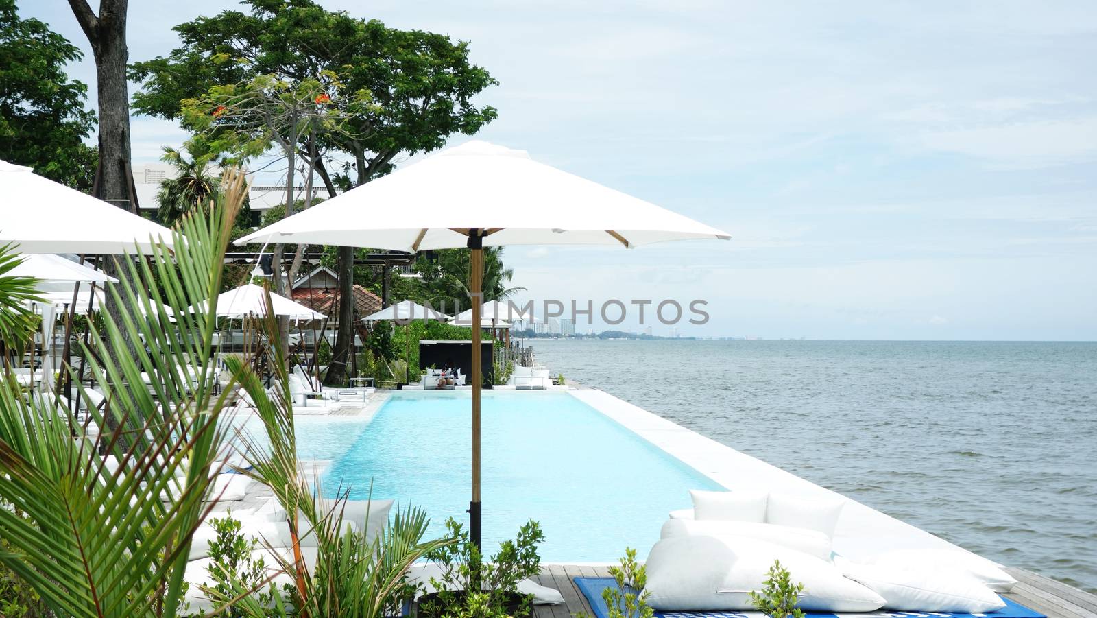 Swimming pool and cafe bar near the beach. Luxury cafe restaurant on Swimming pool bar at the seaside blue ocean.