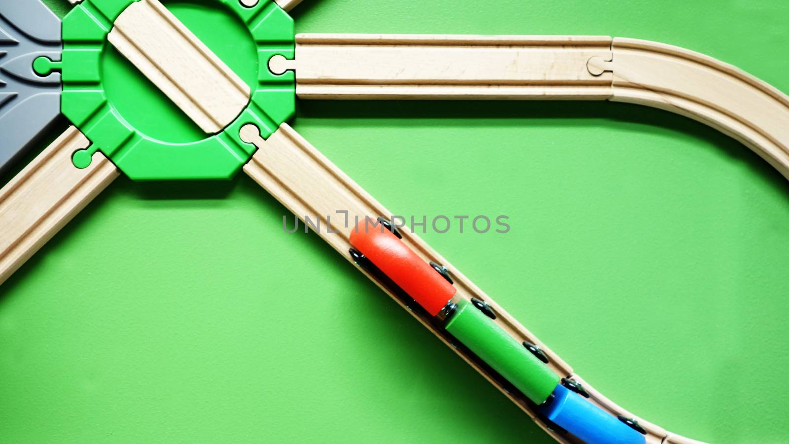 TOP VIEW: Wooden toy train move on curve wooden railways. Green background                        