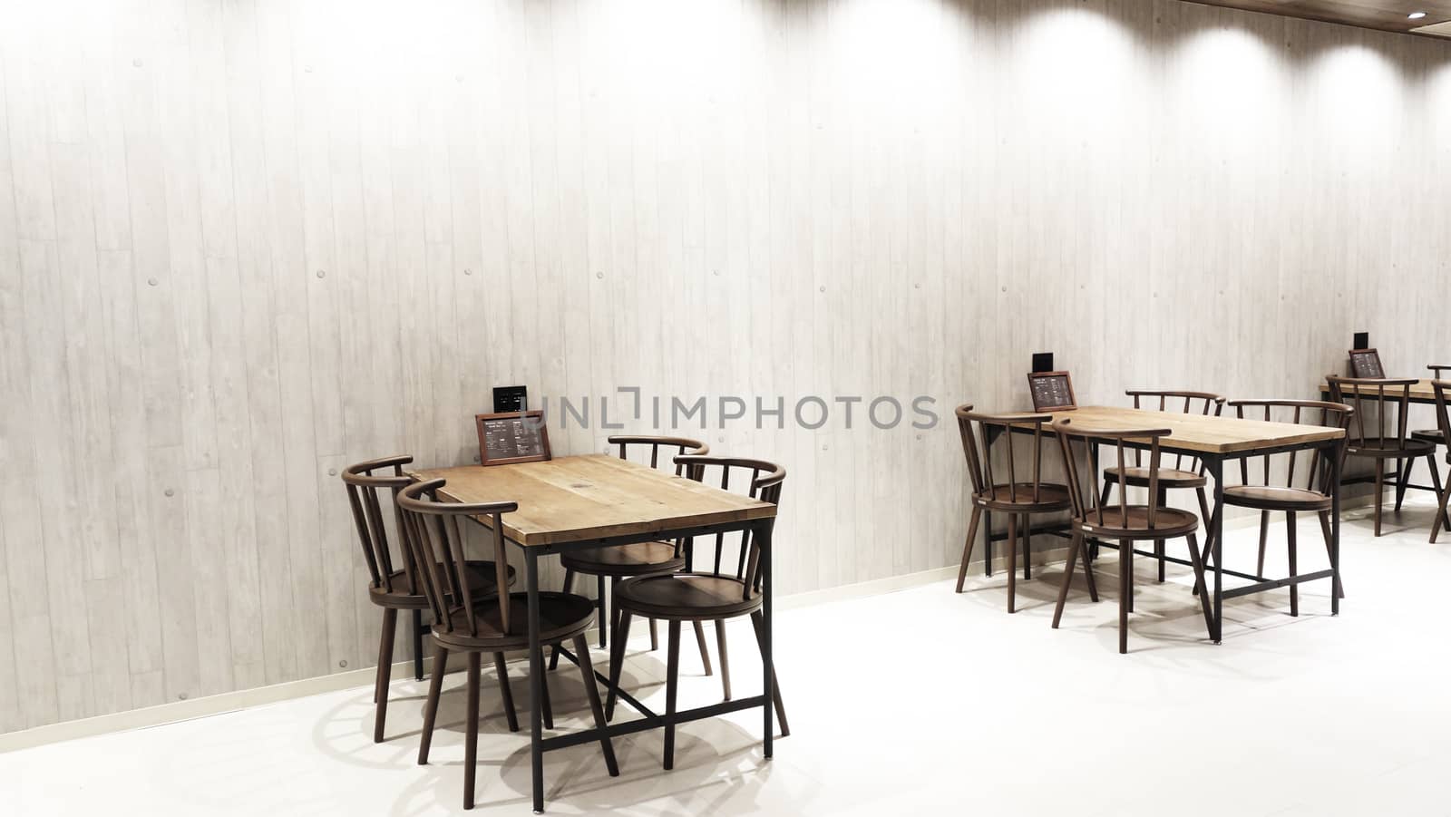 Wooden table and chair in the restaurant . Interior of restaurant food and beverage cafe with wooden table and chairs, food menu on the tabble and vintage wooden background.                                