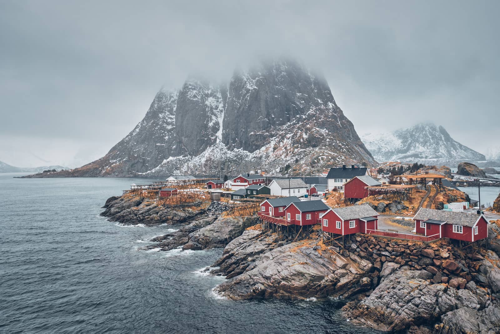Famous tourist attraction Hamnoy fishing village on Lofoten Islands, Norway with red rorbu houses. With falling snow in winter
