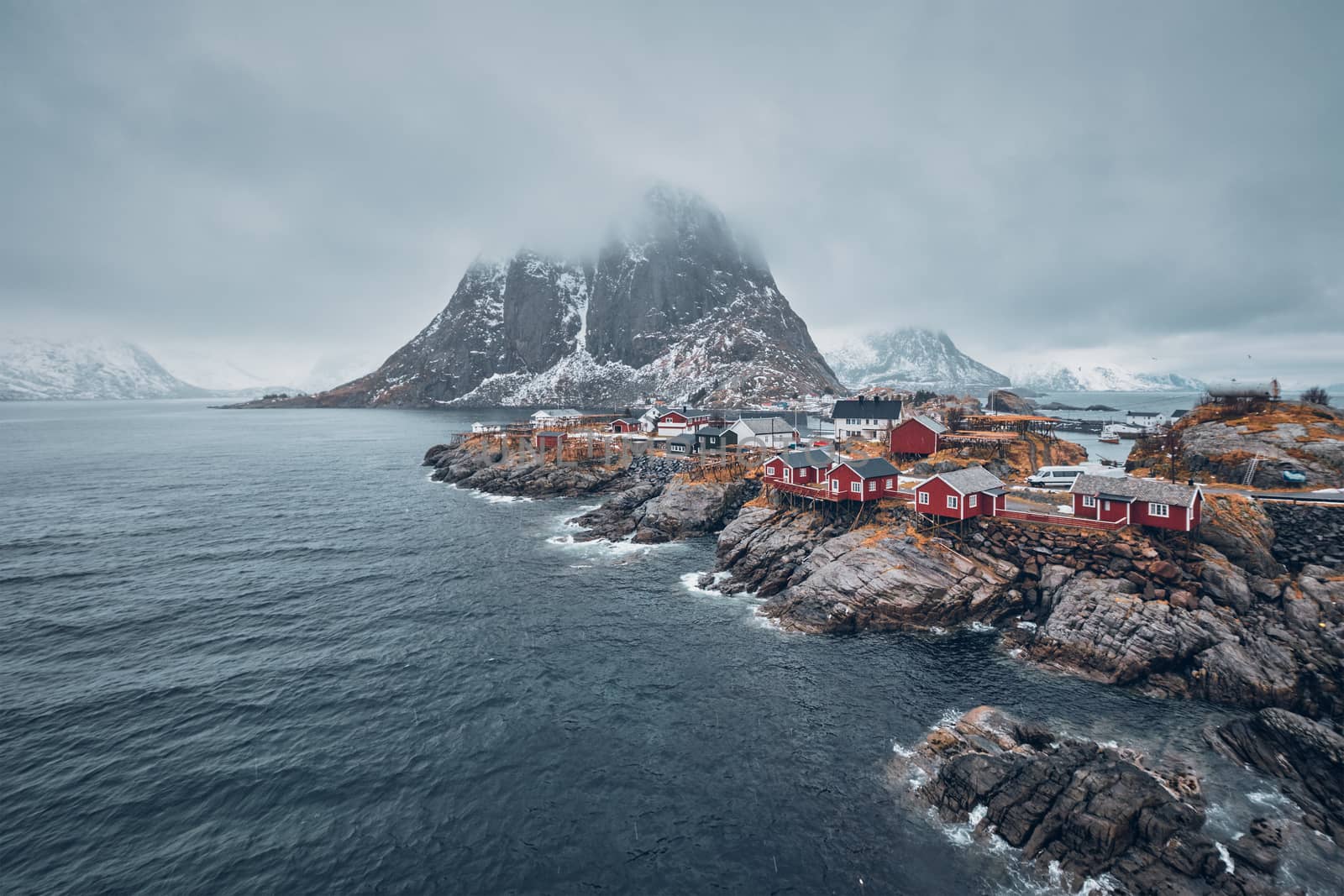 Famous tourist attraction Hamnoy fishing village on Lofoten Islands, Norway with red rorbu houses. With falling snow in winter