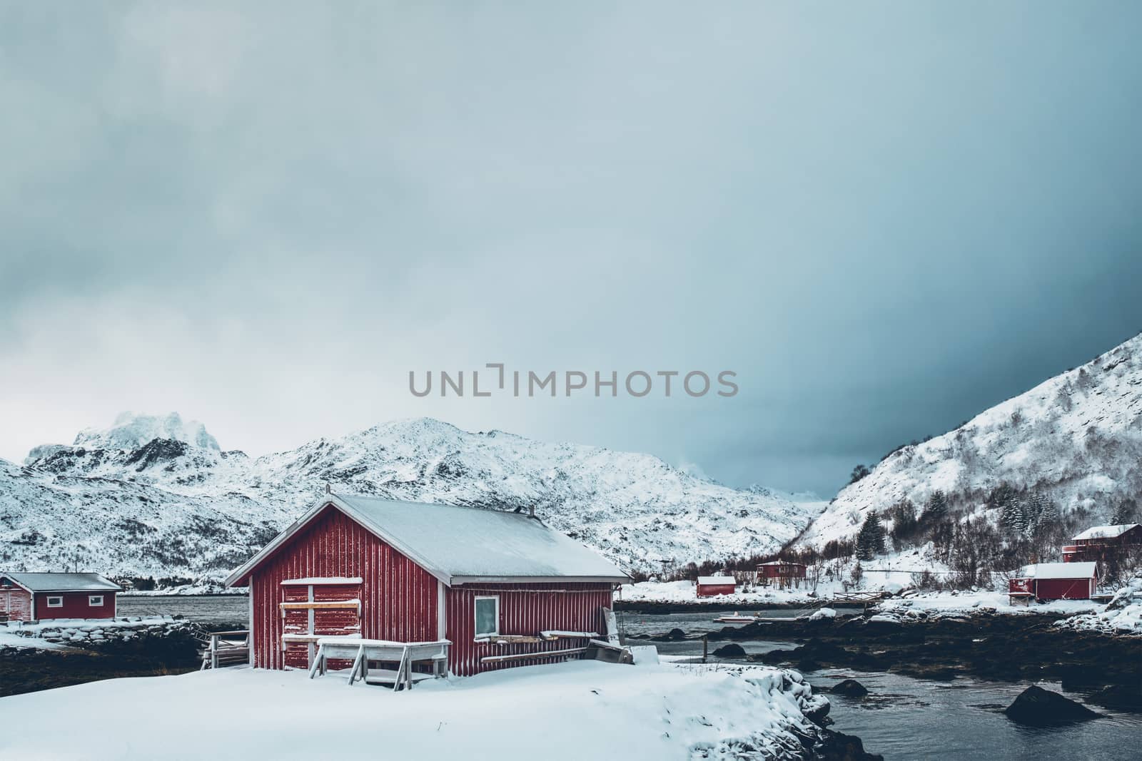 Traditional red rorbu house on fjord shore with heavy snow in winter. Lofoten islands, Norway