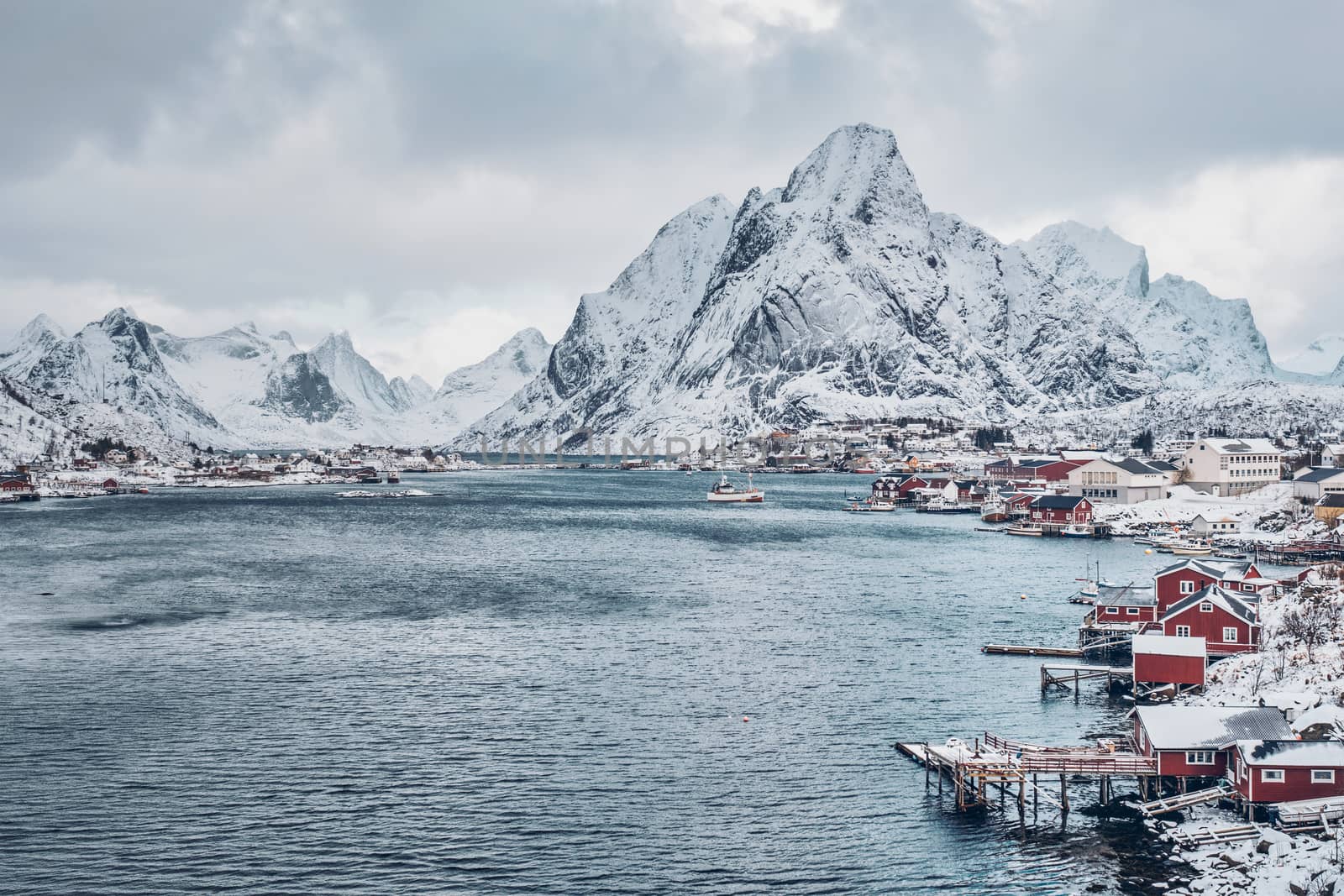 Reine fishing village on Lofoten islands with red rorbu houses in winter with snow. Norway