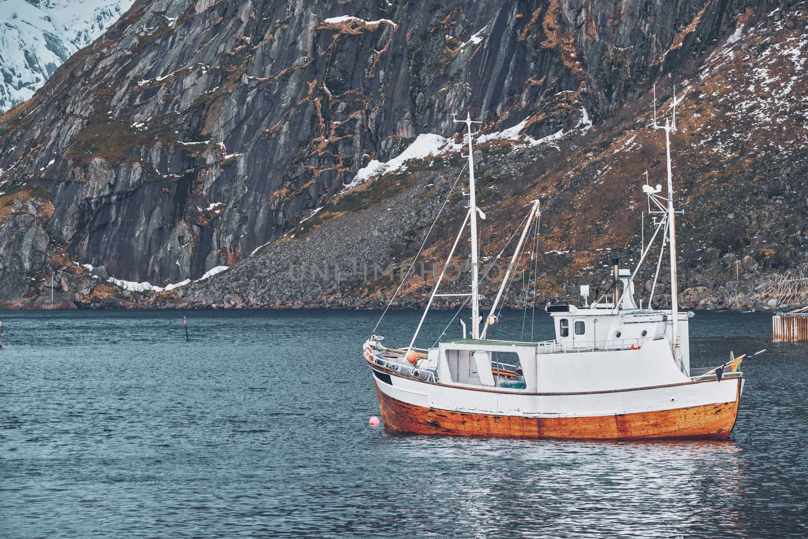 Ship fishing boat in Hamnoy fishing village on Lofoten Islands, Norway with red rorbu houses. With falling snow