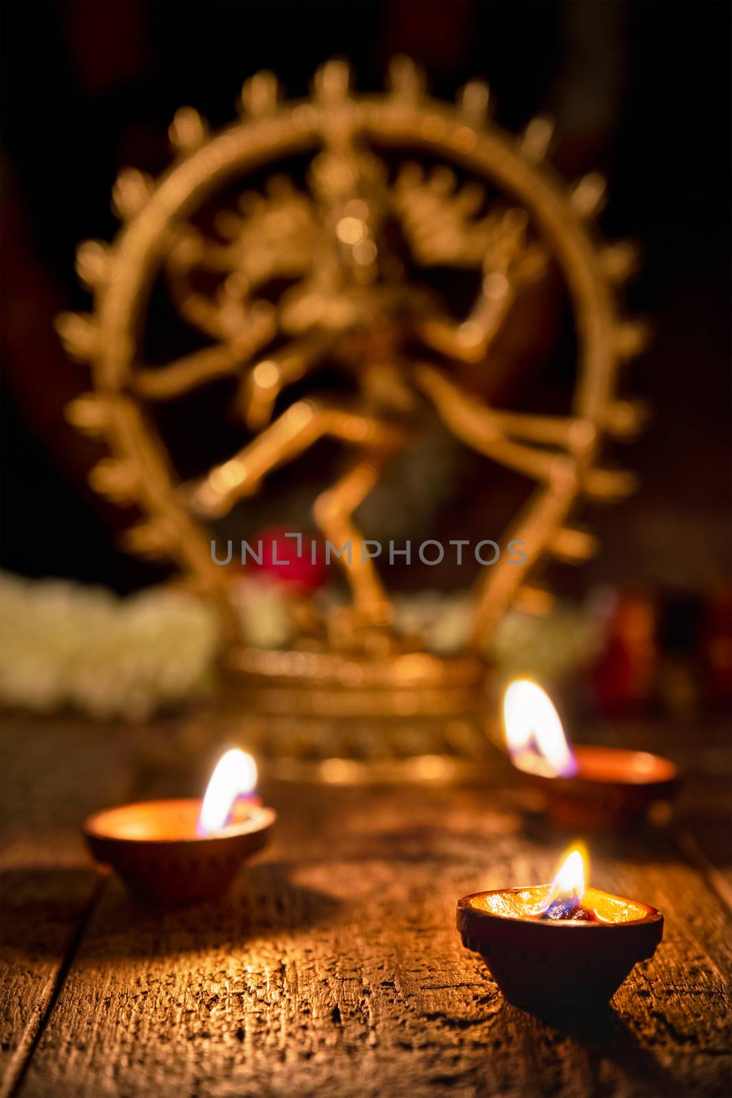 Maha Shivaratri or Diwali concept - Shiva Nataraja statuette with Diwali lights oil ghee candles, focus on lights, India