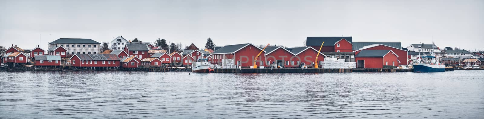 Panorama of Reine fishing village on Lofoten islands with red rorbu houses, pier and fishing boats in winter. Norway