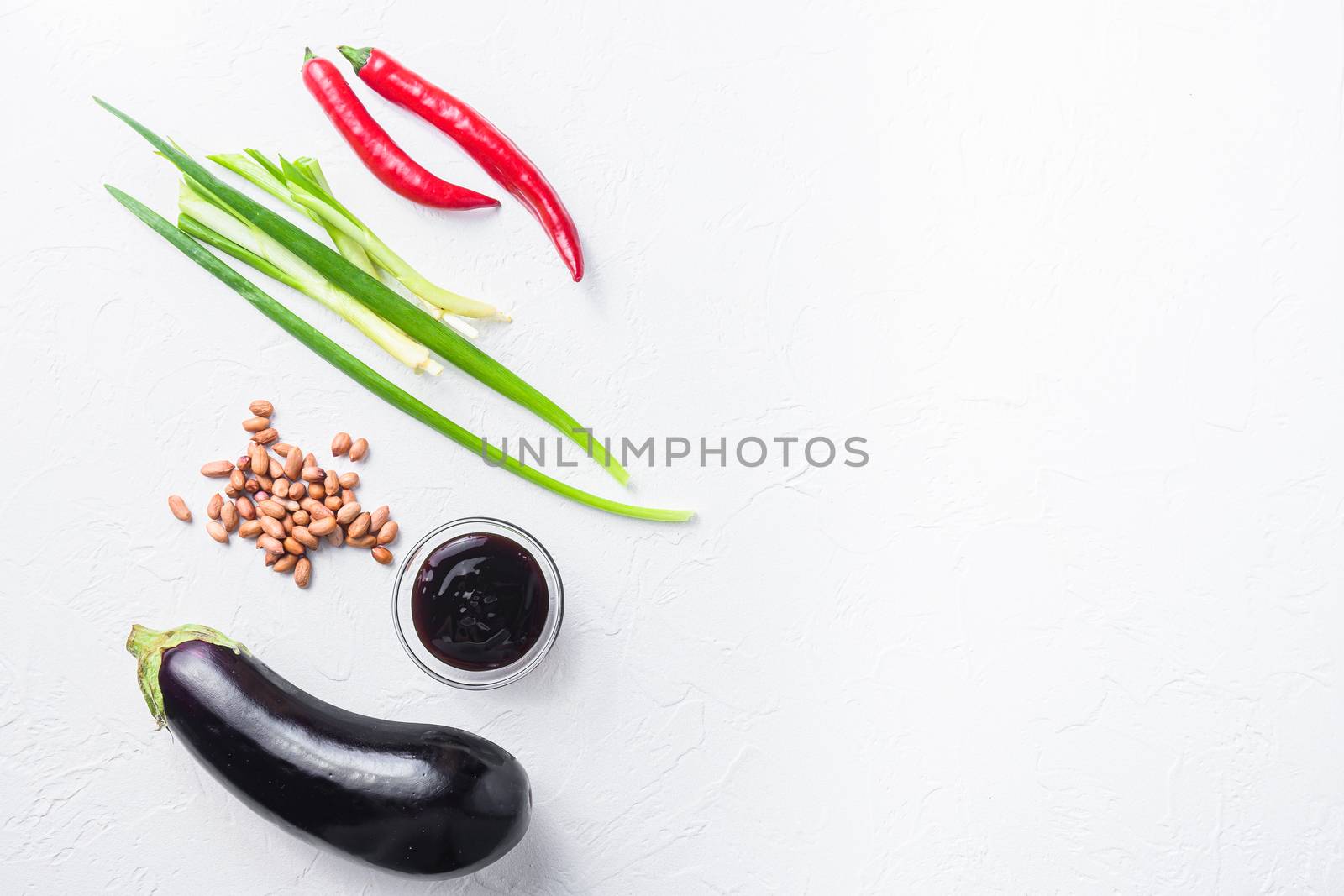 Baked aubergine ingredients, for cooking or grill chili pepper, eggplant, sauce, nuts on white background top view space for text.