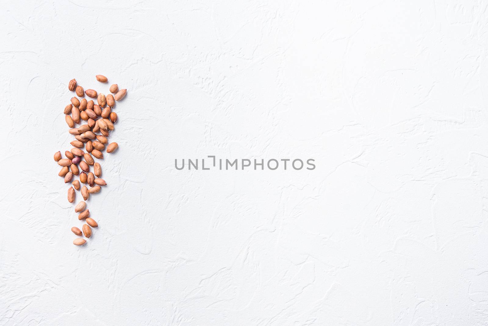 peeled peanuts on white concrete textured background top view space for text