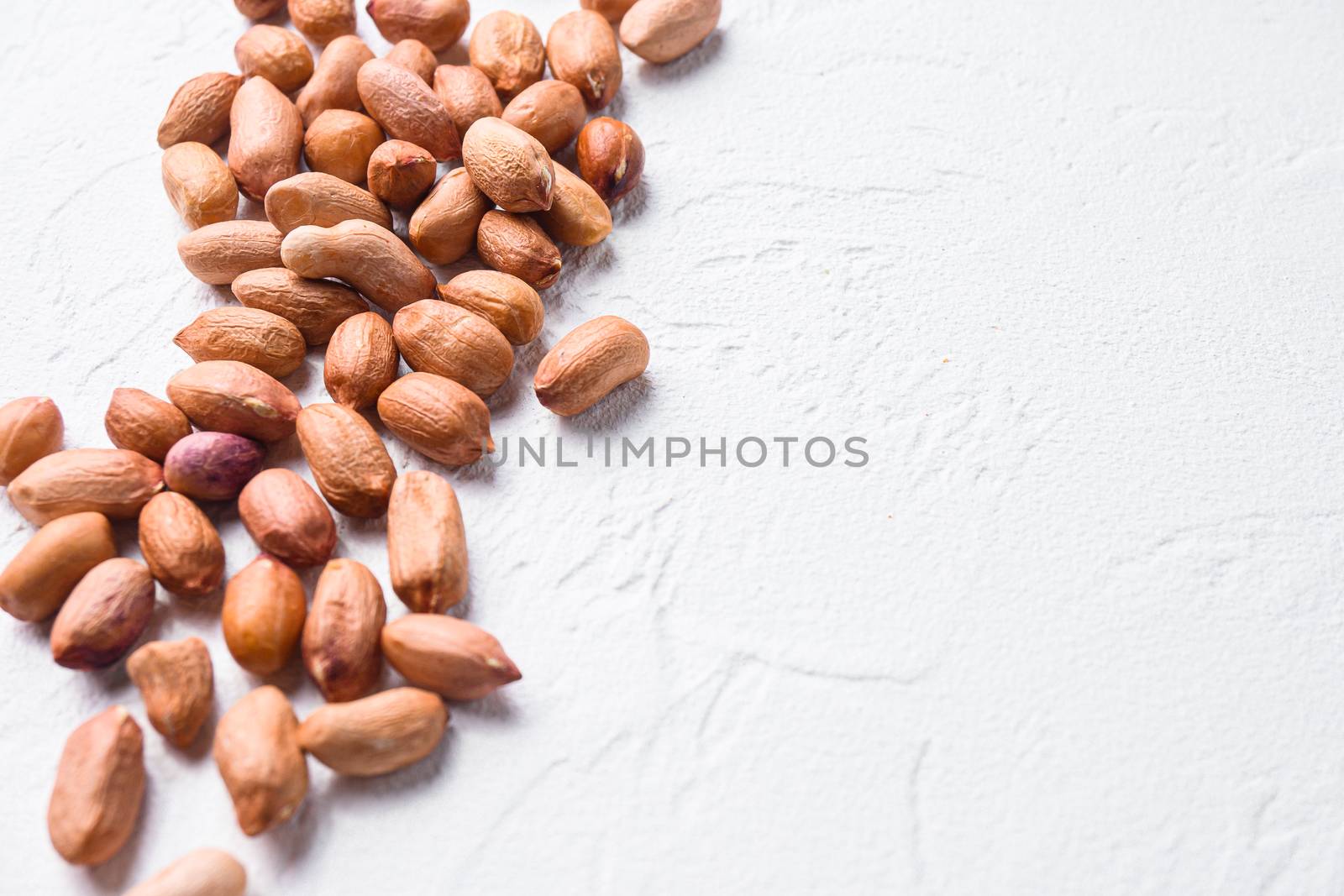 peeled peanuts on white concrete textured background side view selective focus close up space for text