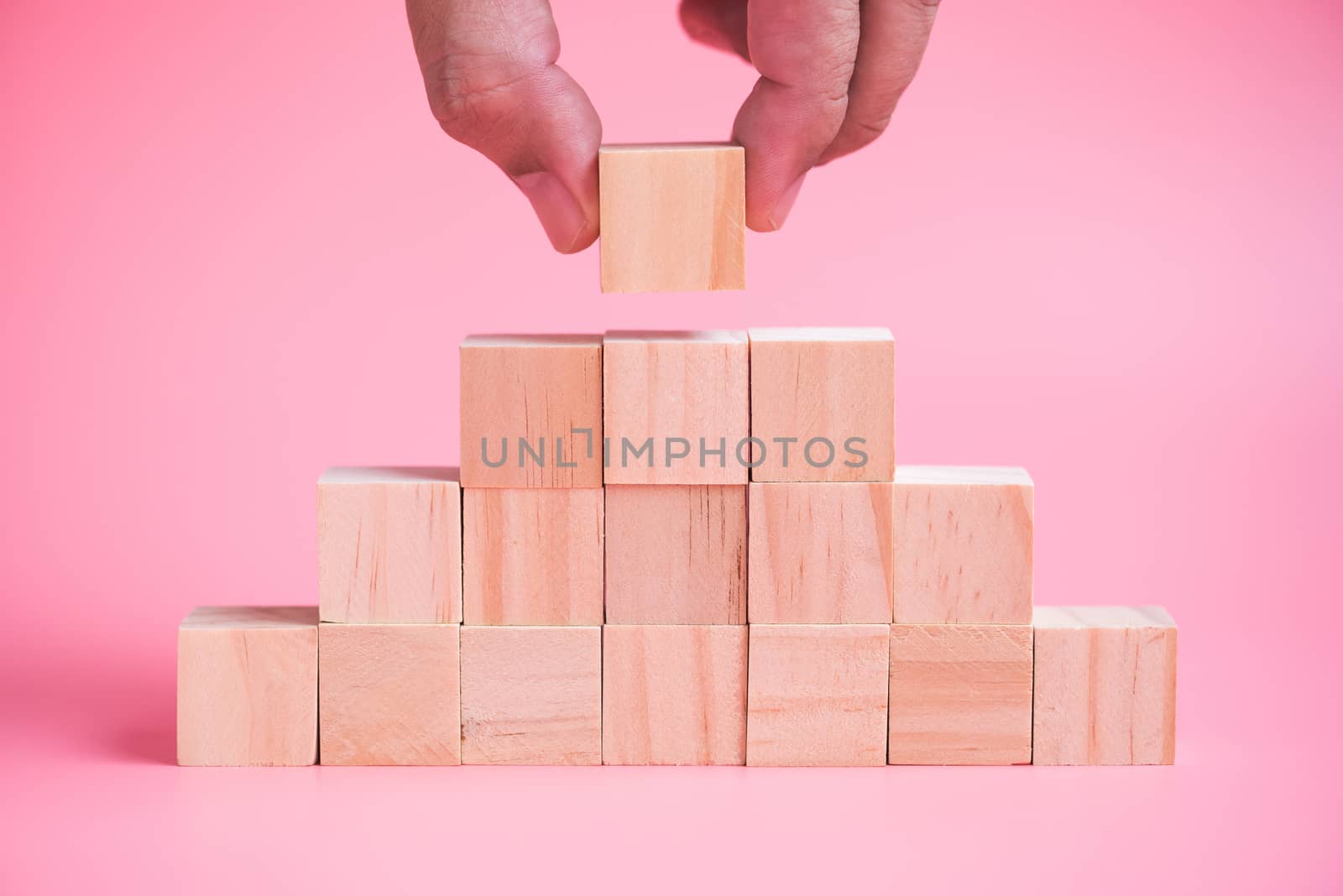 man hand building stack of wood cube building blocks.