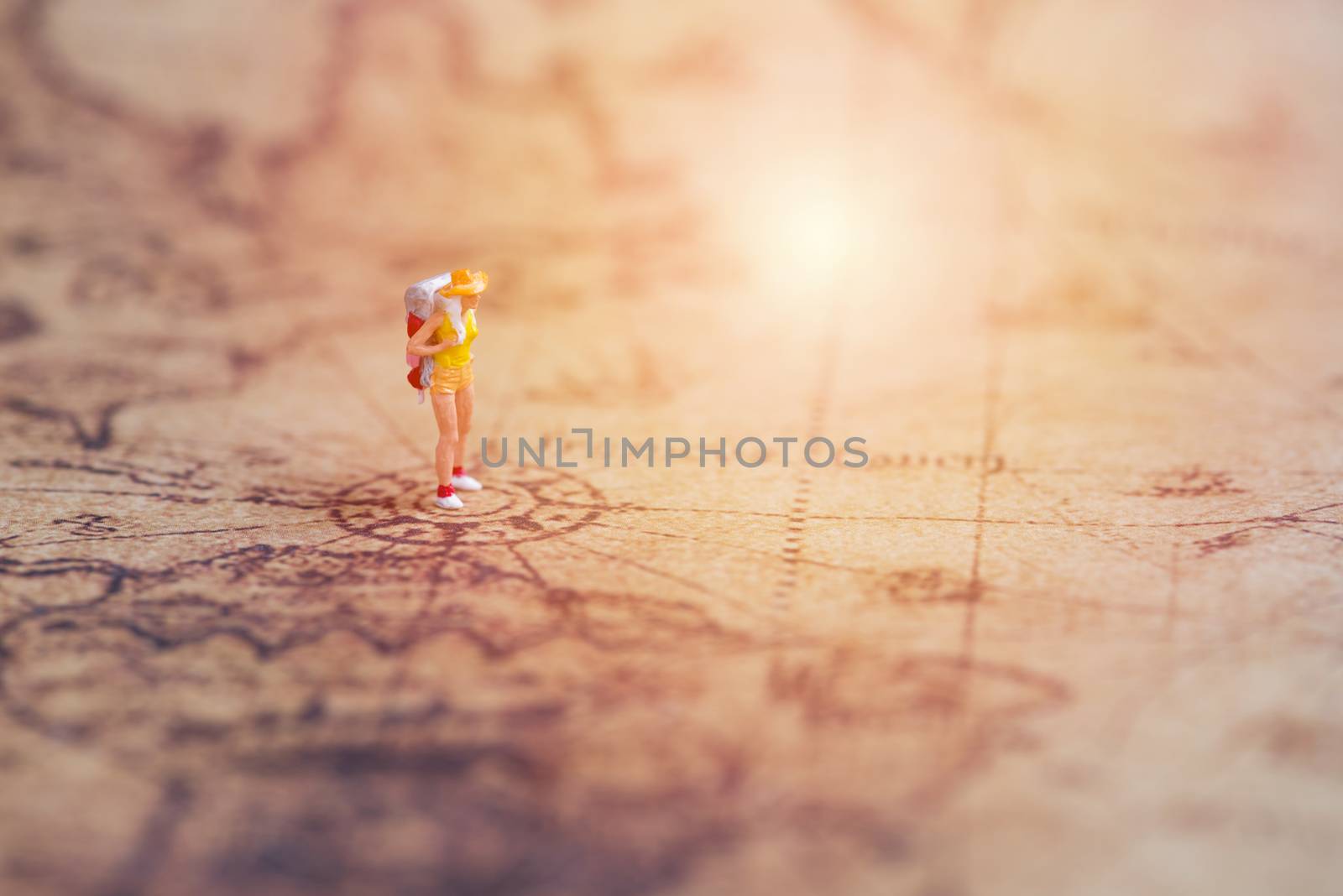 miniature traveler on vintage world map