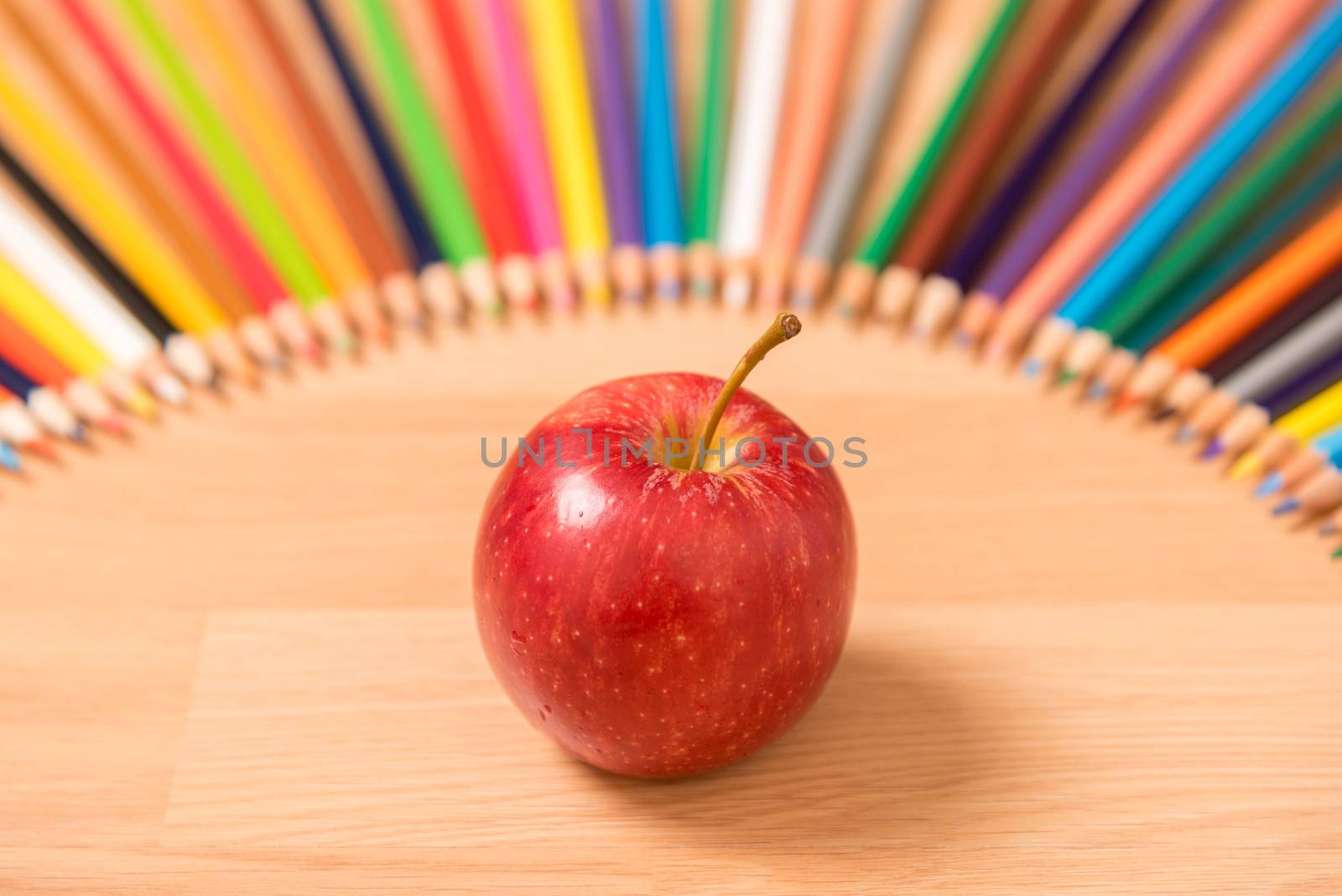 red apple with pencils around.