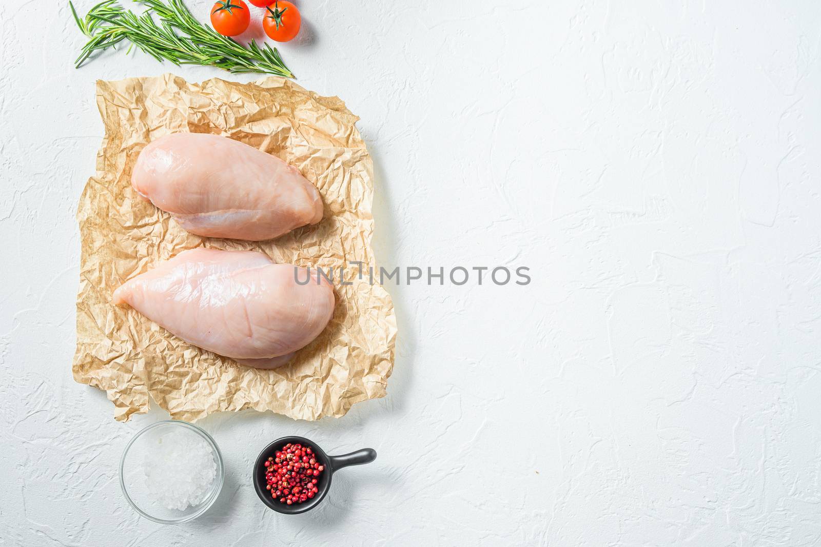 Raw meat, ready for grill or barbeque chicken breast filet, with herbs and spices on craft paper over white background, top view space for text