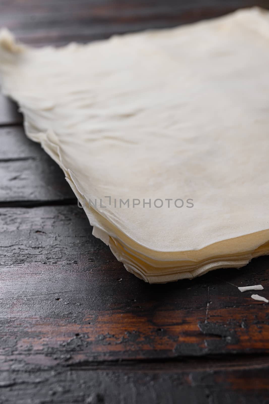 Filo dough for cooking over old dark wooden table side view. by Ilianesolenyi