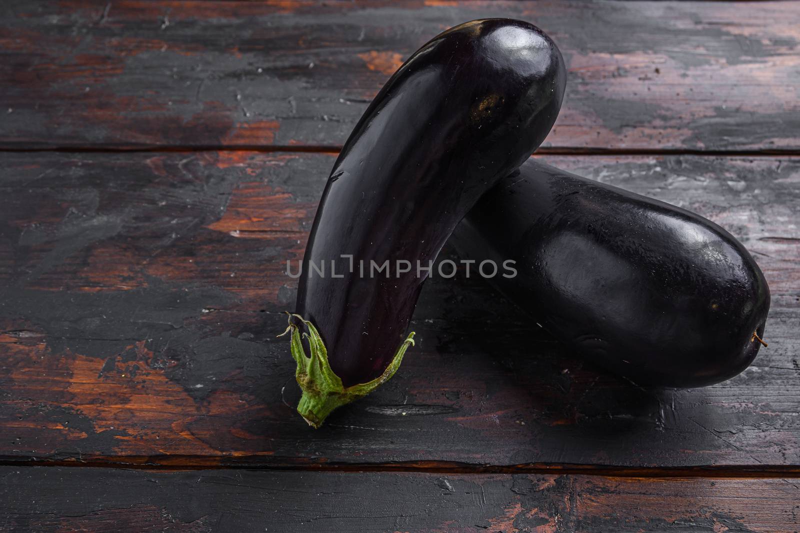 Fresh healthy raw Purple aubergine or eggplant on a kitchen old dark wooden table. Side view, space for text. by Ilianesolenyi