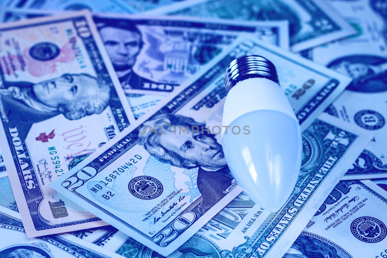 LED lamp on dollar bills background. The concept of saving money on electricity.