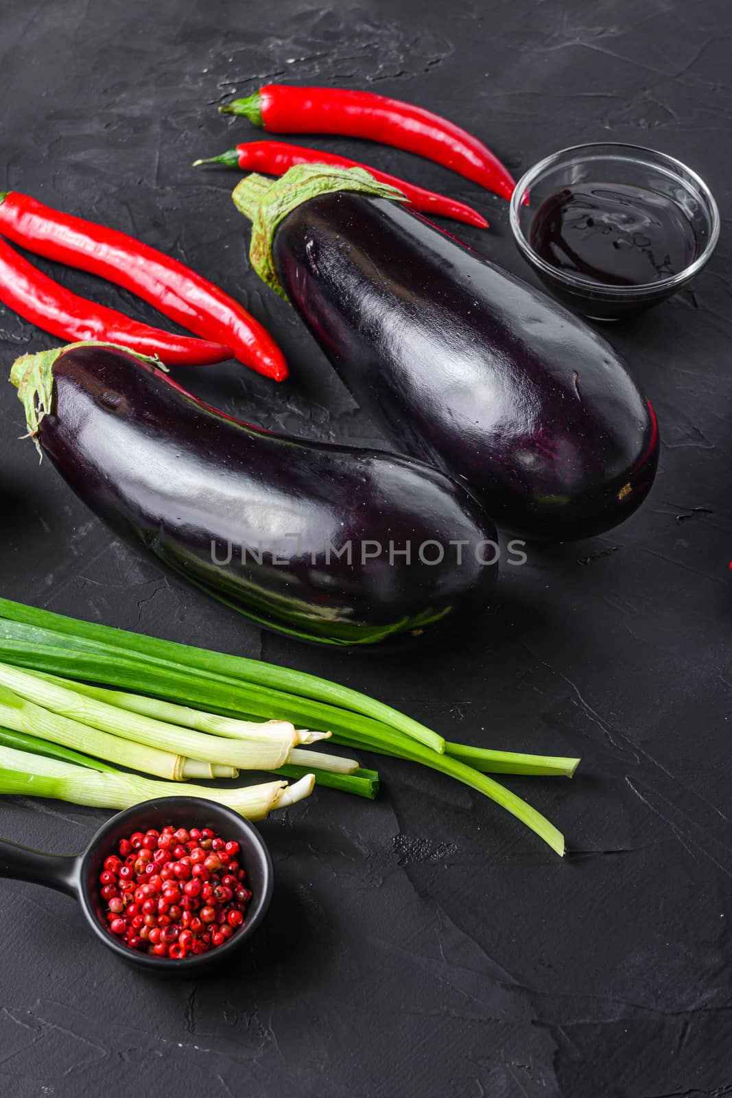 Sticky teriyaki aubergine ingredients, for cooking or grill chili pepper, eggplant, sauce, nuts on black background side view