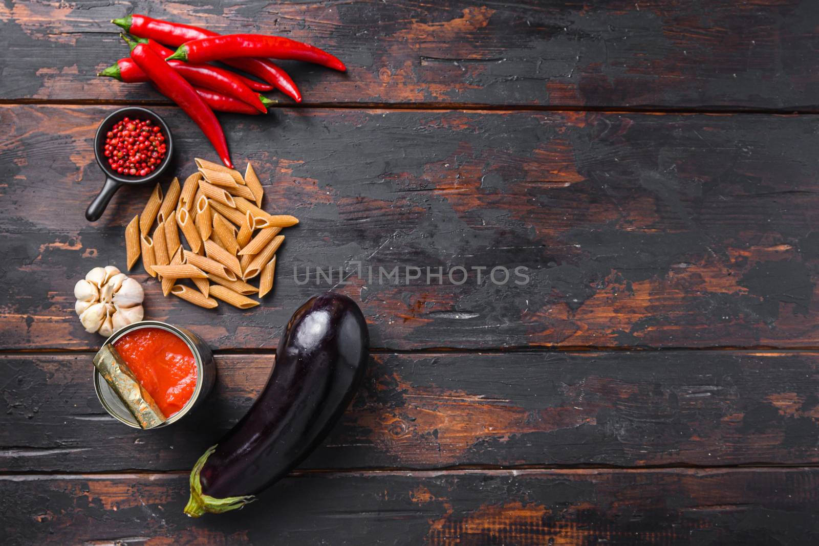 Aubergine penne ingredients eggplant pasta, pepper tomatoe sauce, on old wooden table top view space for text. High quality.