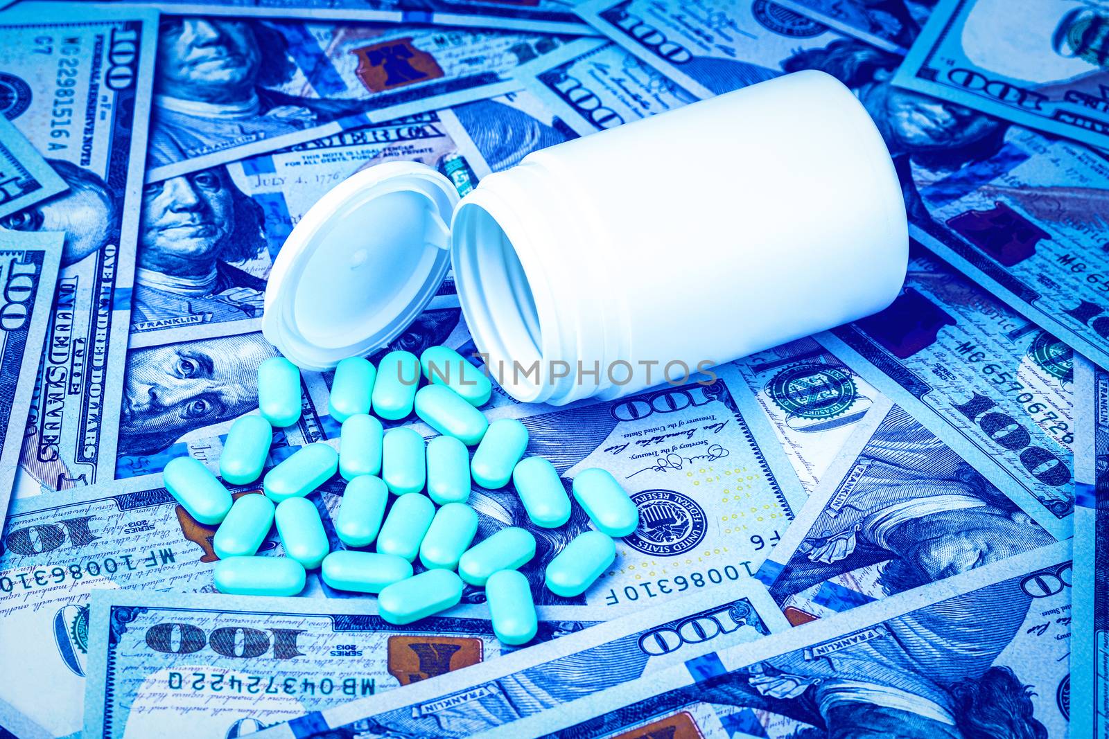 Green pills on the background of one hundred dollar bills. The concept of the expensive cost of healthcare or financing medicine. White medicine bottle with copy space for text.