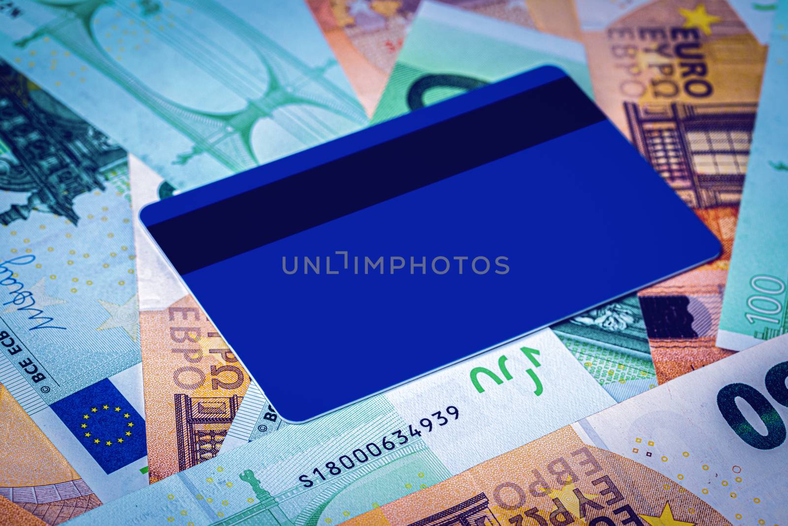 Euro bills and blue debit card with copy space for a text. The concept of electronic money and commerce. The concept of buying things on credit. Background or mock up for design.