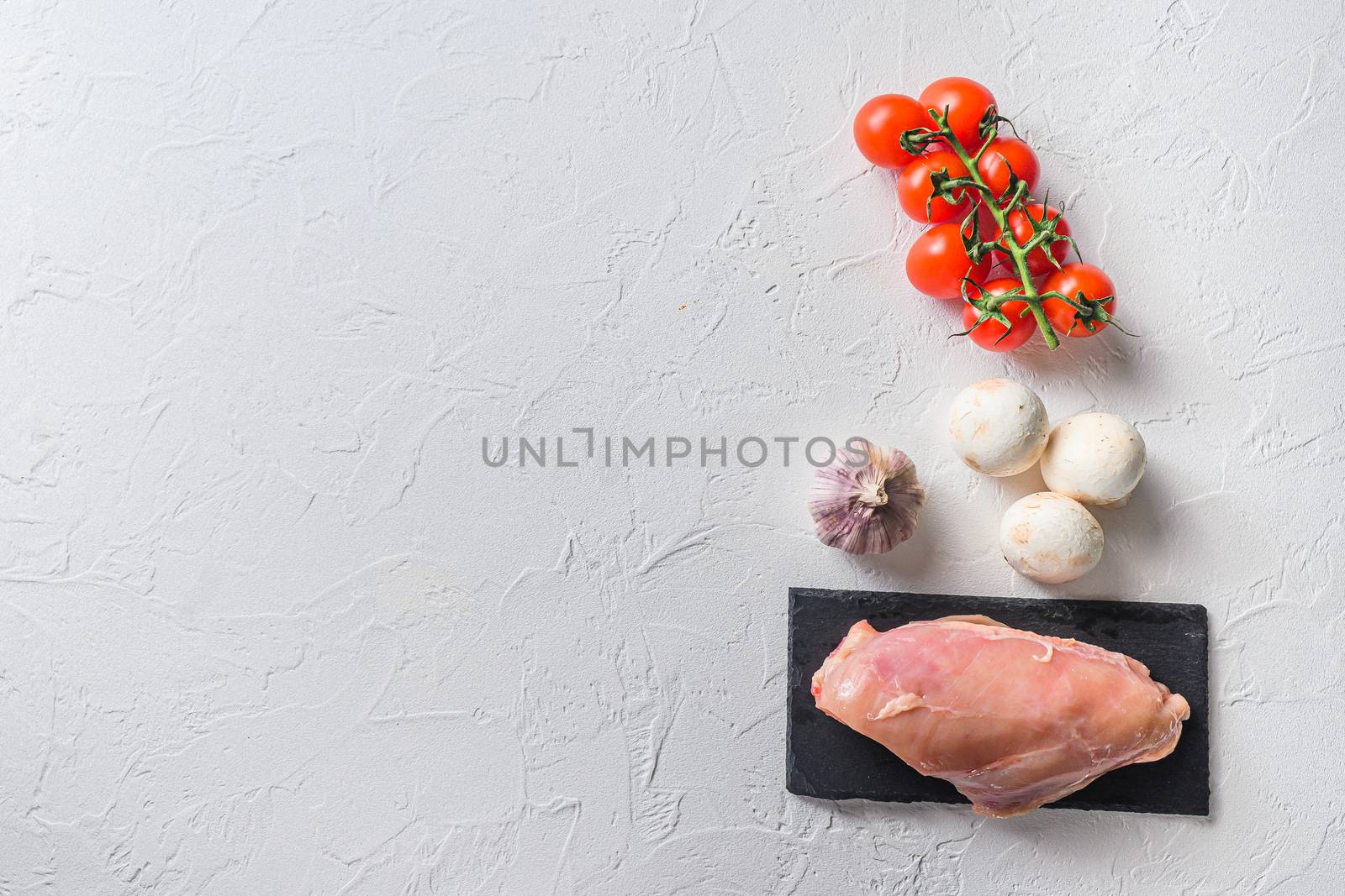 Raw chicken breast on stone board over white background