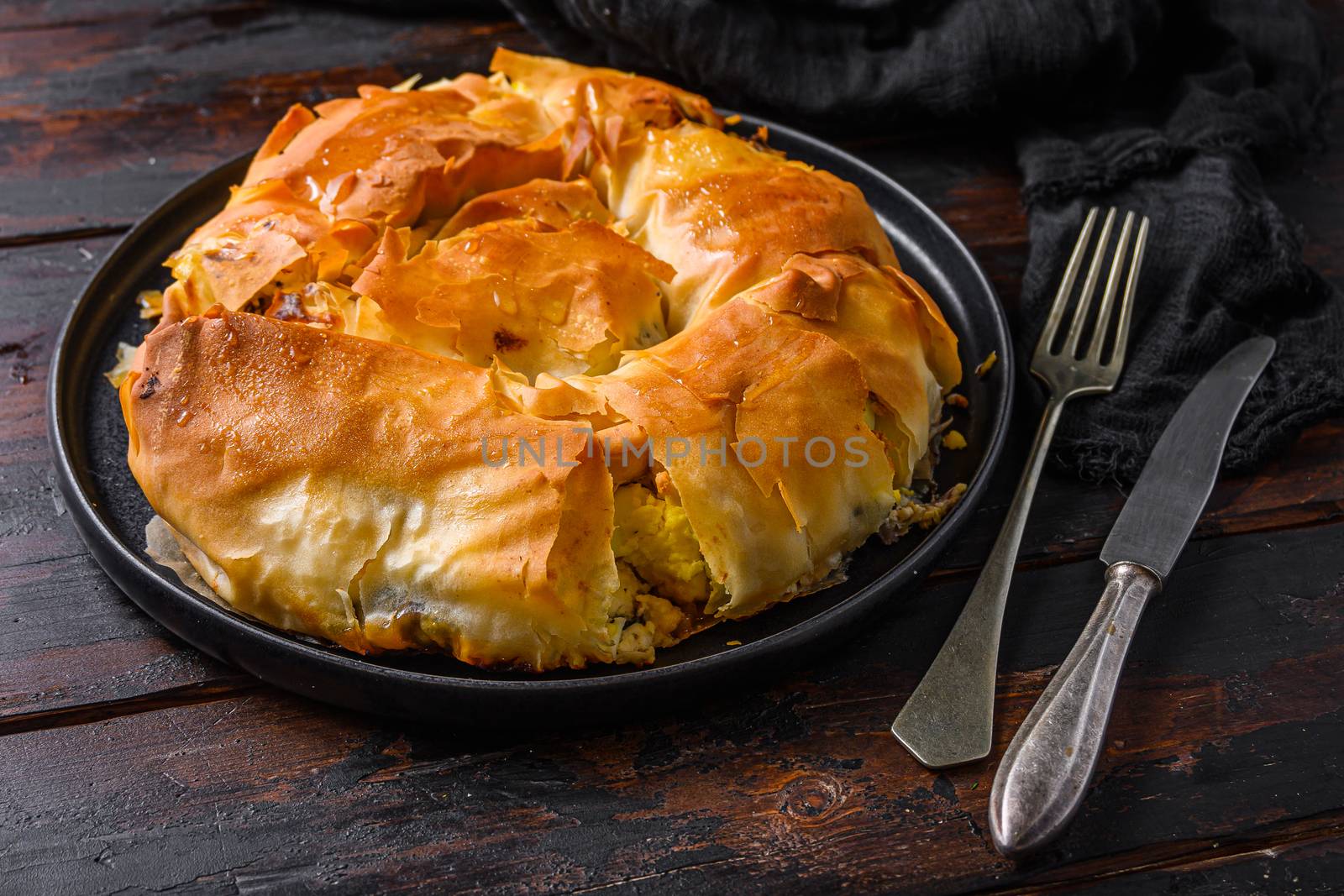 Homemade Greek spanakopita in on black plate filo spinach eggs feta side view on dark wooden background. by Ilianesolenyi