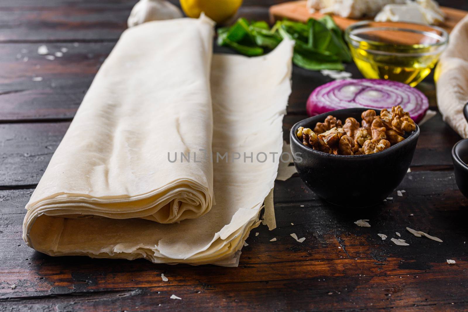 Greek spanakopita ingredients filo spinach eggs feta side view on dark wooden background.