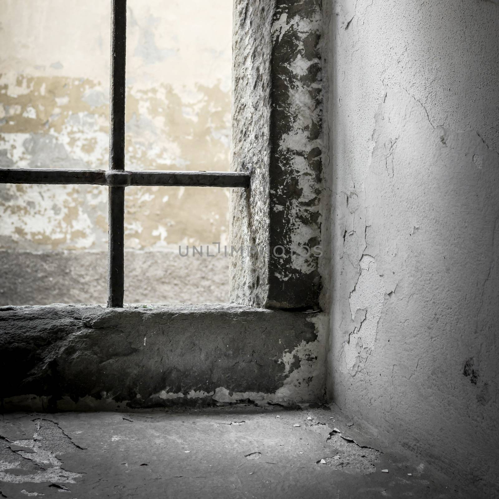 Old grunge prison with sun rays breaking through a barred window. Shallow DOF.
