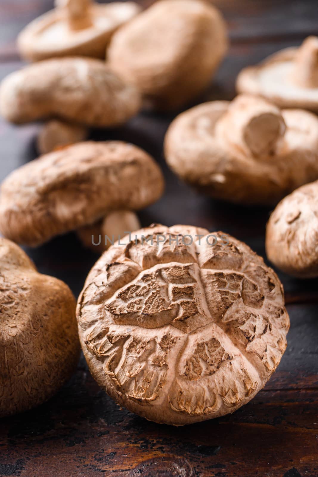 Shiitake mushrooms set on old wooden table, side view selective focus by Ilianesolenyi