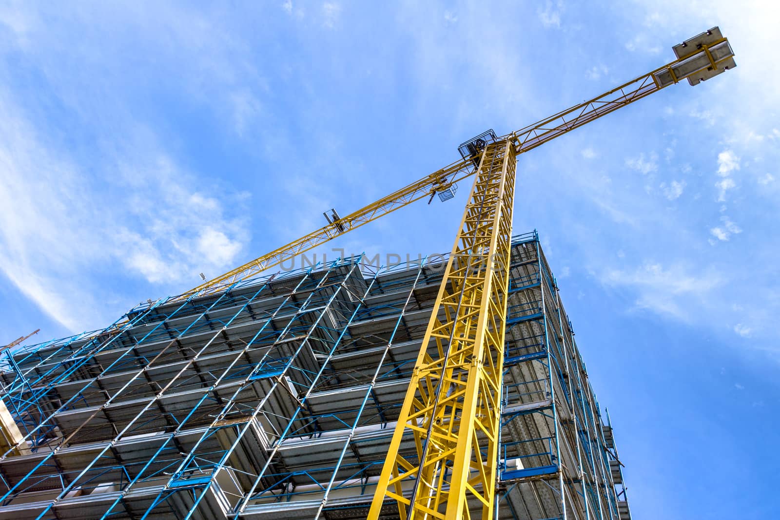 Extensive scaffolding providing platforms for work in progress on a new apartment block. Construction site. Housing crane operation. High rise Building Under Construction.