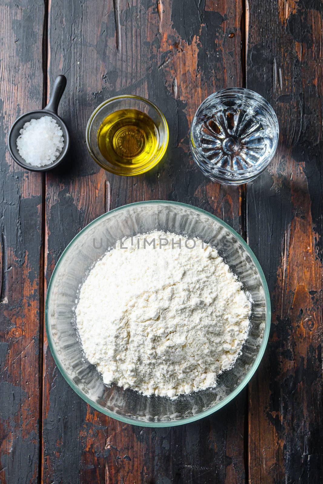 Ingredients for the dough, flour oil water and salt on wood background.