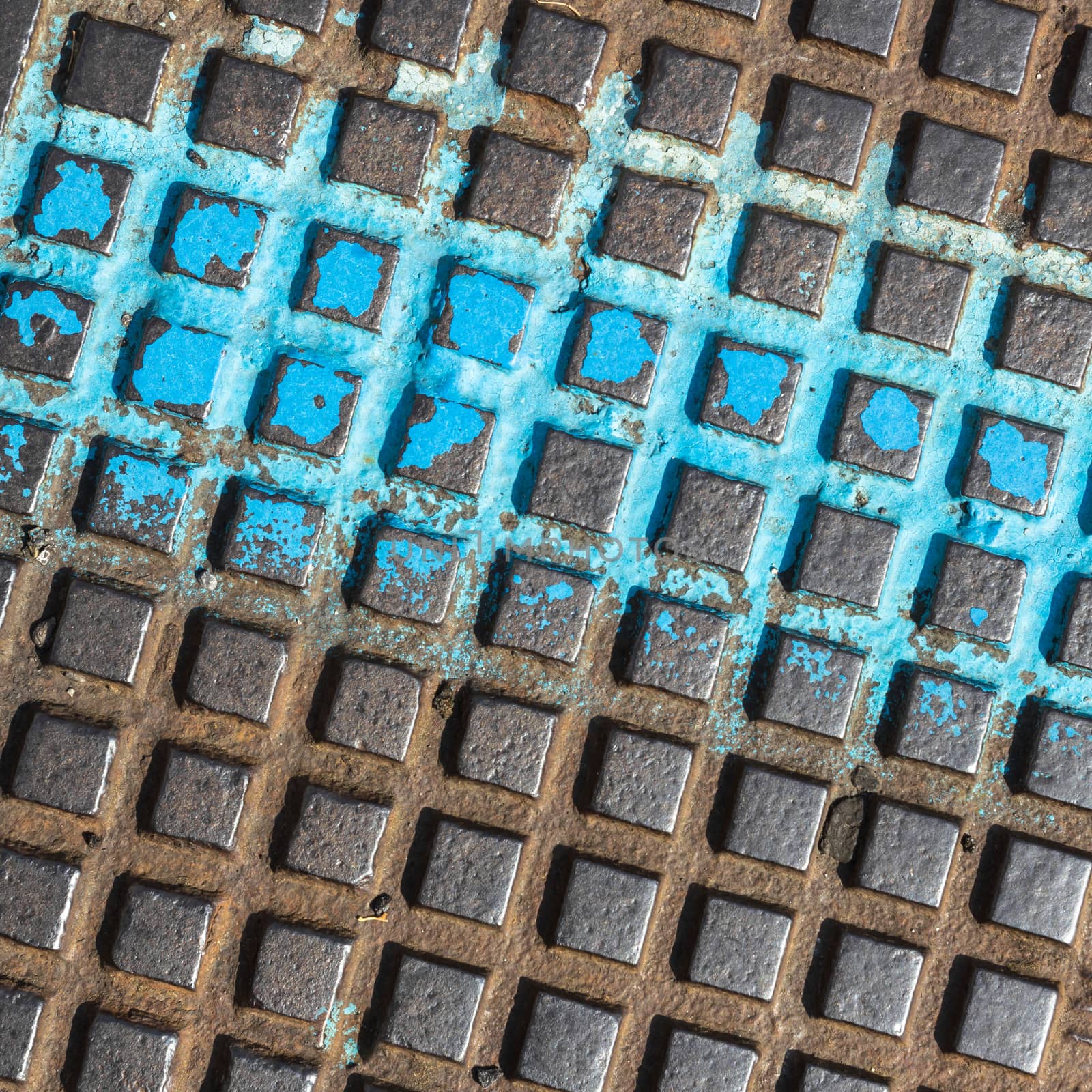 Close - up of a brown and blue manhole cover. Grunge metal background .