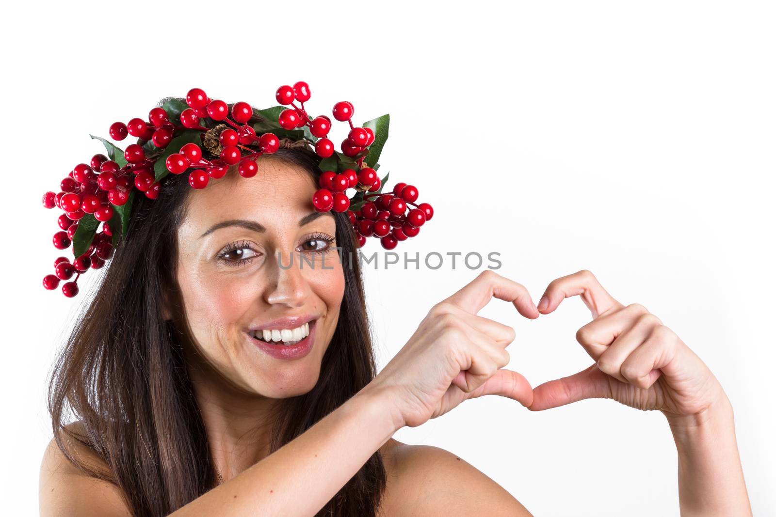 Christmas or New Year beauty woman portrait isolated on white background. Smiling young woman with wearing a Christmas wreath on her head making a heart with her hands. Natural makeup.