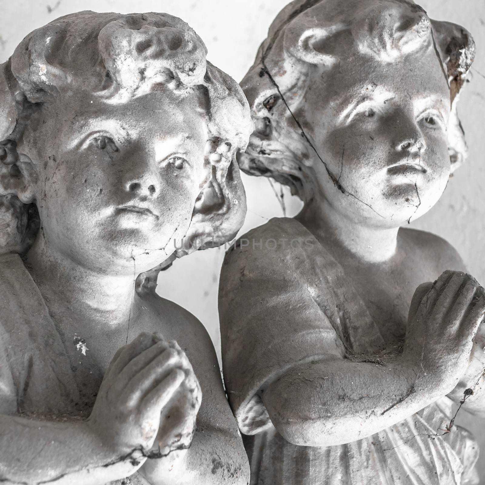 Statues of children in prayer covered with cobwebs.