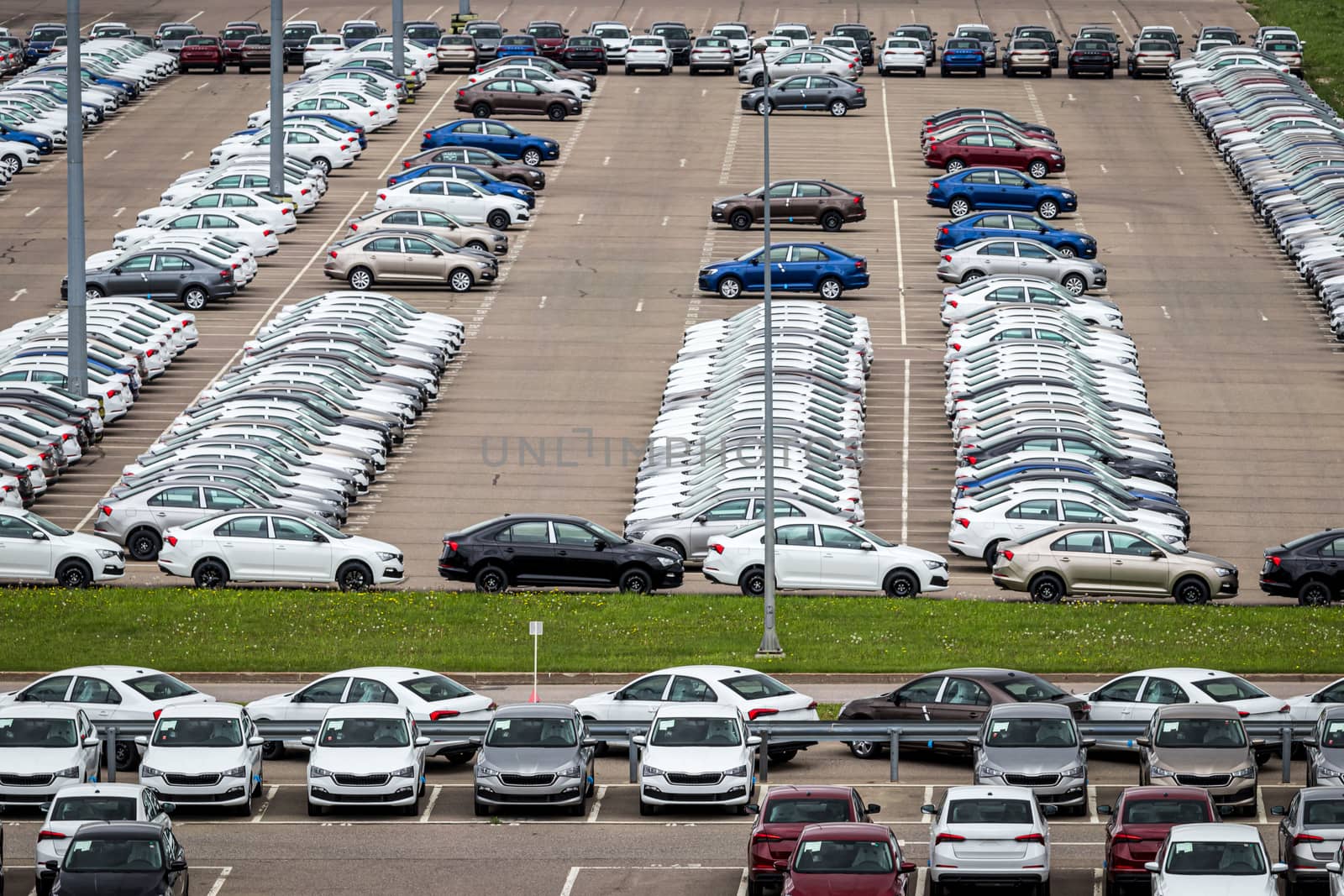 Rows of a new cars parked in a distribution center of a car factory. Top view to the parking in the open air.