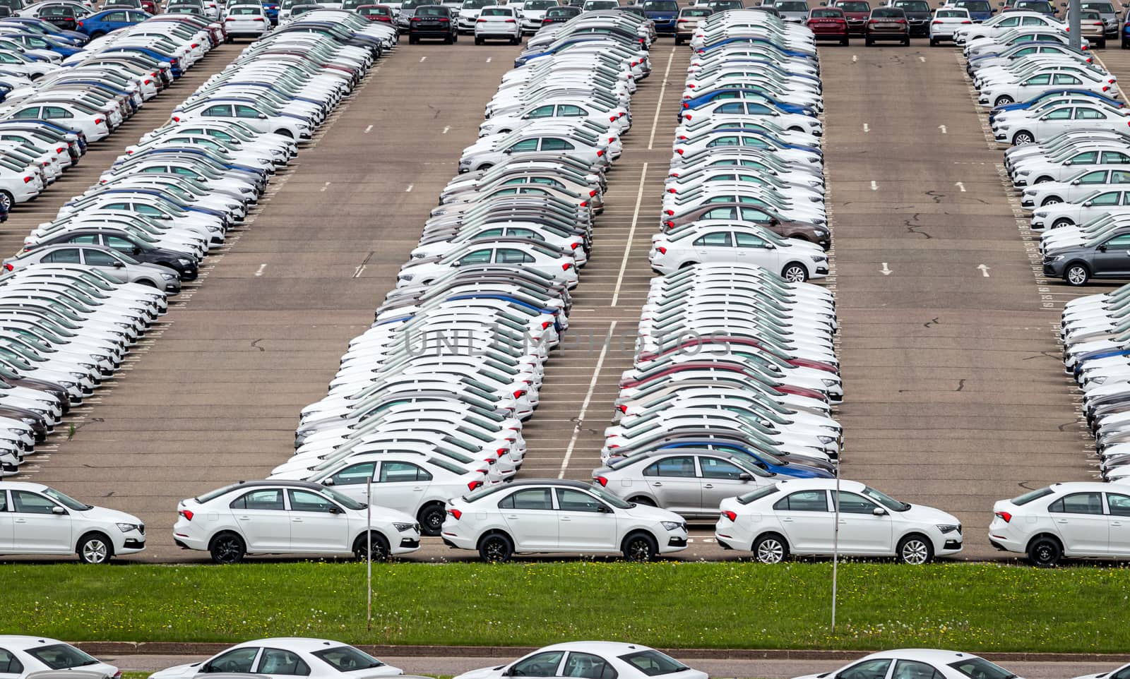 Rows of a new cars parked in a distribution center of a car factory. Top view to the parking in the open air.