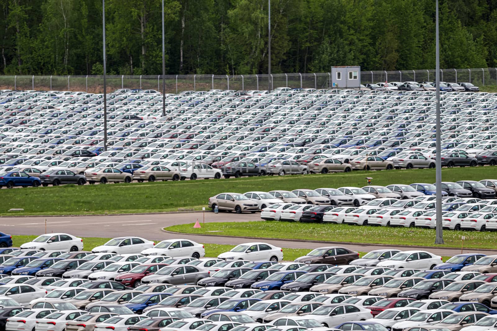 Rows of a new cars parked in a distribution center of a car factory. Top view to the parking in the open air.