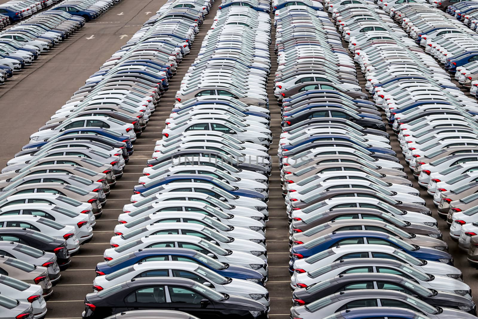 Rows of a new cars parked in a distribution center of a car factory. Top view to the parking in the open air. by Eugene_Yemelyanov