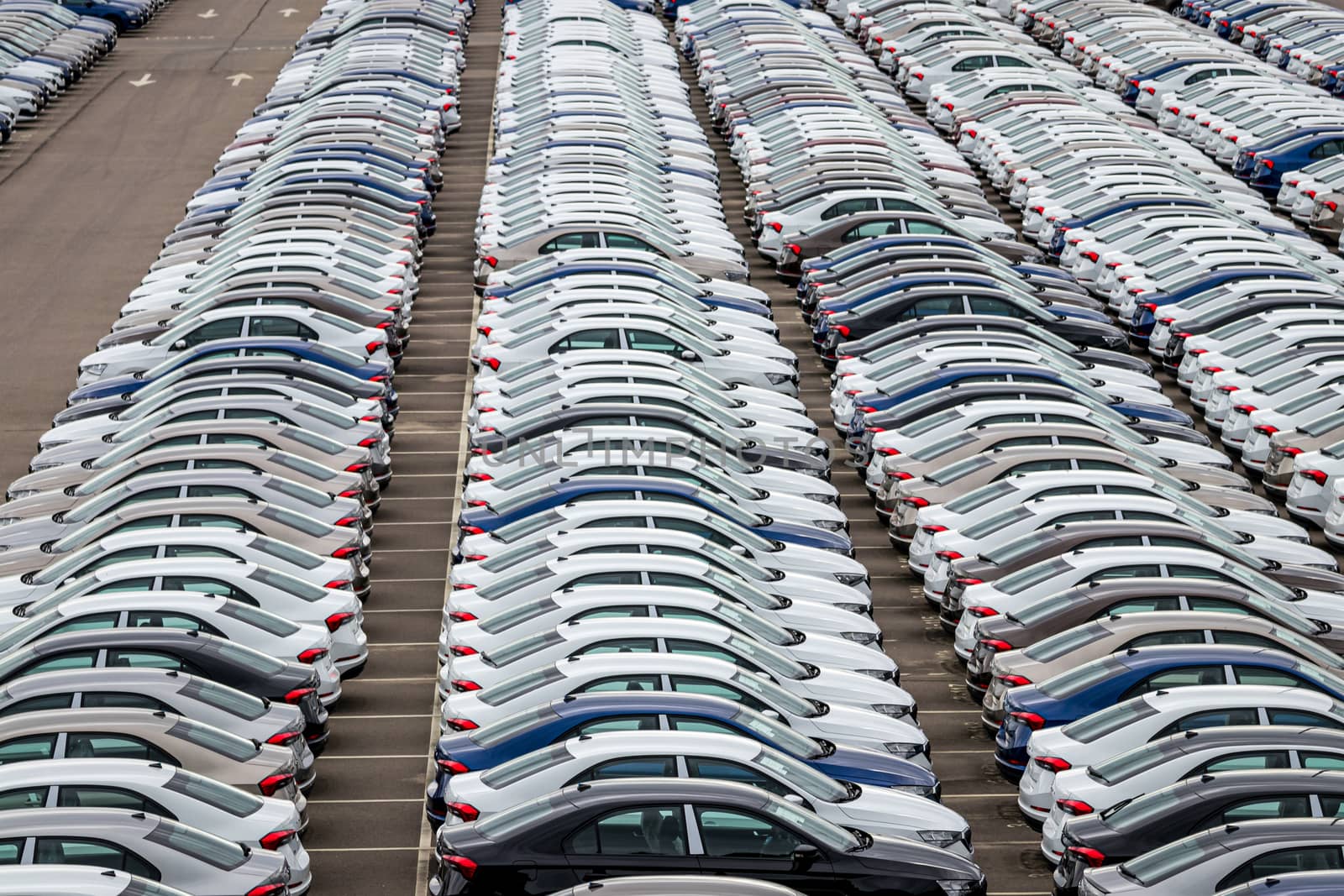 Rows of a new cars parked in a distribution center of a car factory. Top view to the parking in the open air. by Eugene_Yemelyanov