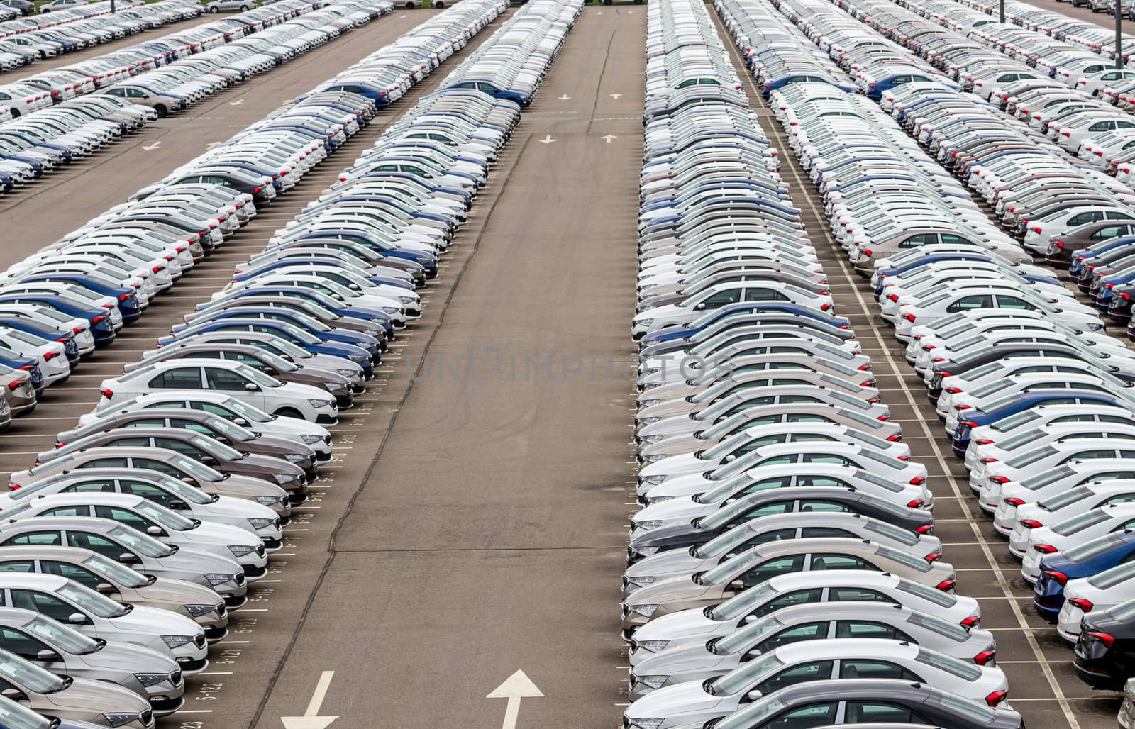 Rows of a new cars parked in a distribution center of a car factory. Top view to the parking in the open air. by Eugene_Yemelyanov